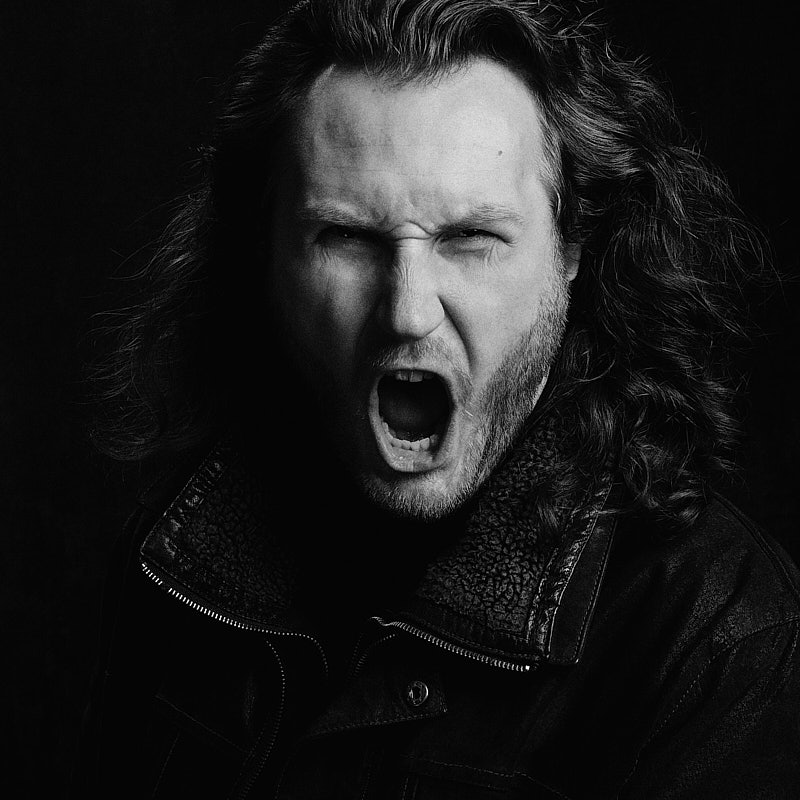 Expressives Schwarz-Weiß-Schauspielerportrait eines schreienden Mannes in Lederjacke für eine professionelle Sedcard, fotografiert in Freising.