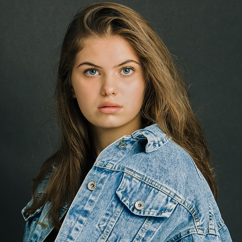 Natürliches Headshot-Portrait einer jungen Schauspielerin in einer Jeansjacke für professionelle Sedcards, fotografiert in Freising.